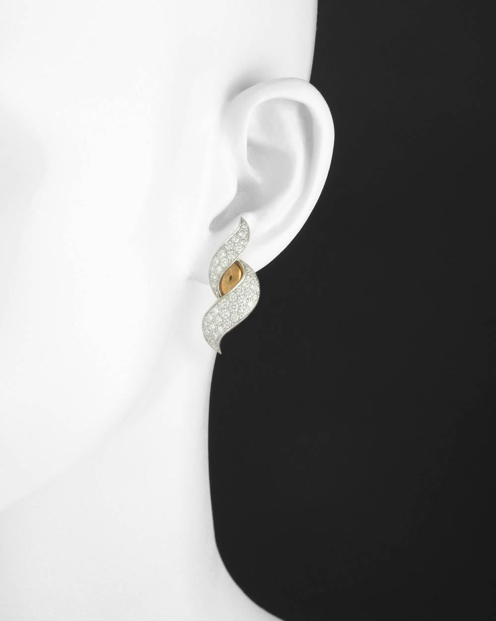 Elegant scroll motif earclips, showcasing two delicate swirling motif pavé-set diamond sections in platinum separated by high-polished 18k yellow gold, with gold clip backs (posts may be added upon customer request), numbered 702283, signed 'HB'