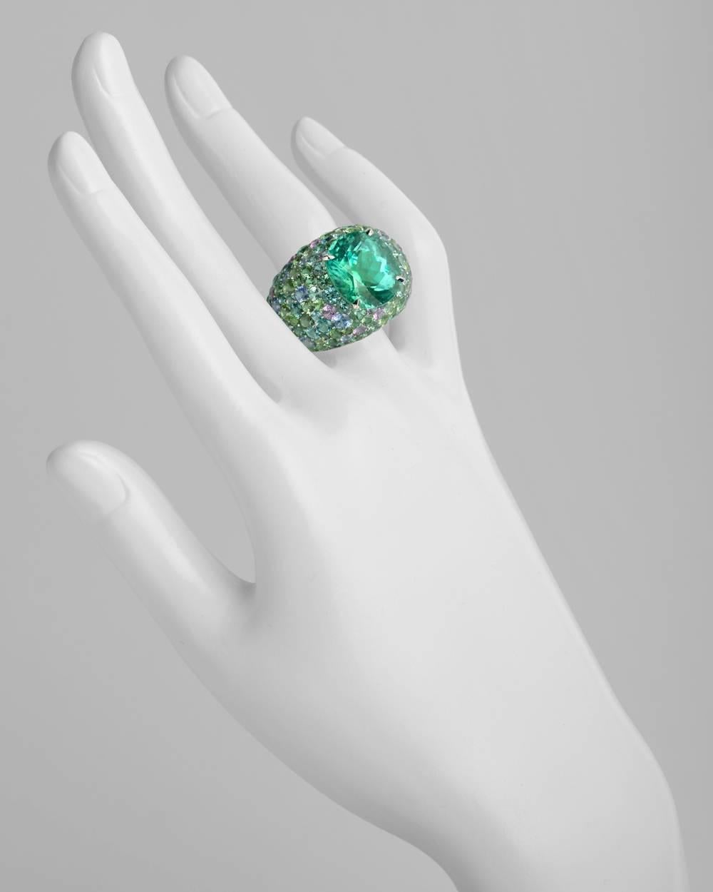 Green tourmaline domed cocktail ring, centering a fine oval-shaped faceted green tourmaline weighing approximately 10.76 carats, surrounded by pavé-set multicolored tourmalines and sapphires, mounted in 18k white gold, signed Lorenz Baumer Paris.