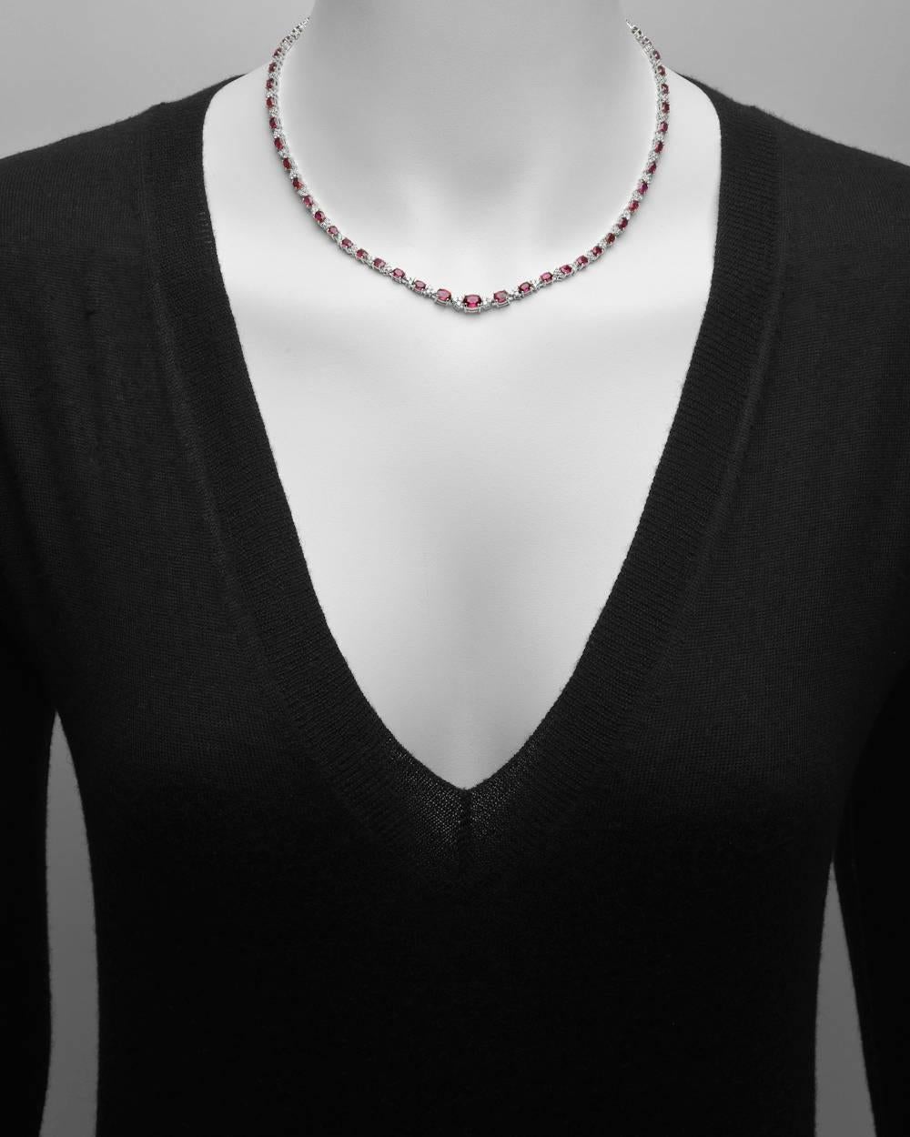 Graduated ruby and diamond line necklace, composed of oval-shaped rubies alternating with clusters of three small round diamonds, mounted in platinum. Rubies weighing approximately 13.00 total carats and diamonds weighing approximately 2.38 total
