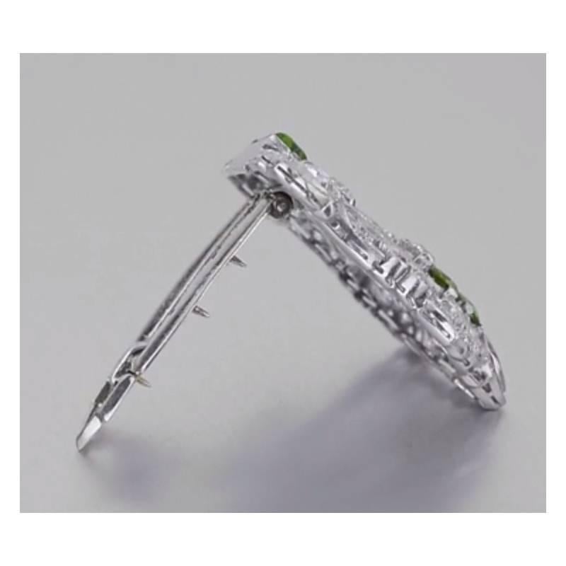 Each Art Deco dress clip of this pair is designed as an openwork geometric plaque with circular and baguette-cut diamonds, set with half-moon-shaped and circular-cut peridots, the diamonds altogether weighing approximately 8.18 total carats, mounted