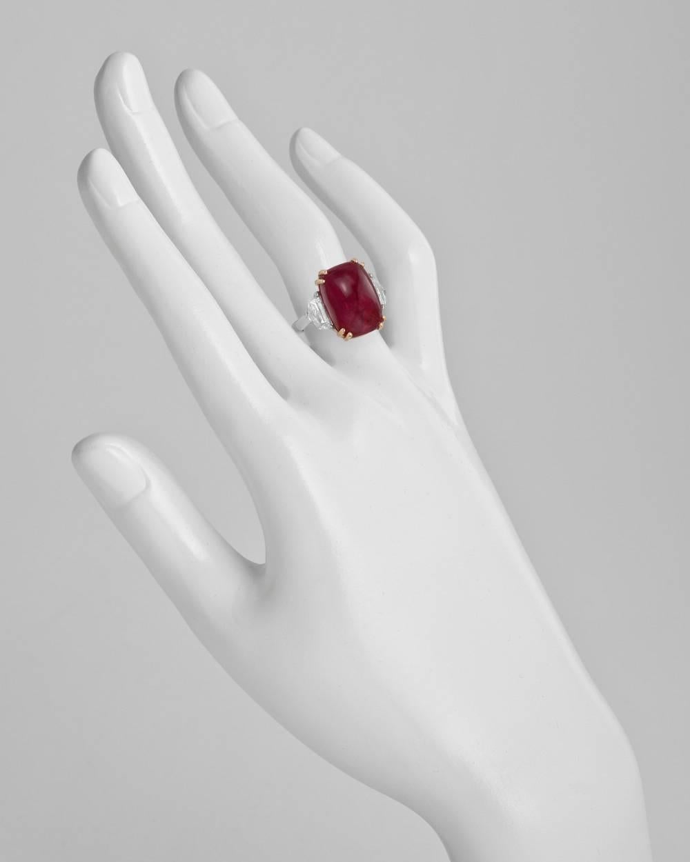 Ruby and diamond ring, centering a sugarloaf cabochon-cut natural ruby weighing 15.15 carats, flanked by two colorless epaulette-cut diamonds weighing approximately 1.31 total carats (F-color, VS1-VS2 clarity), mounted in platinum and 18k yellow