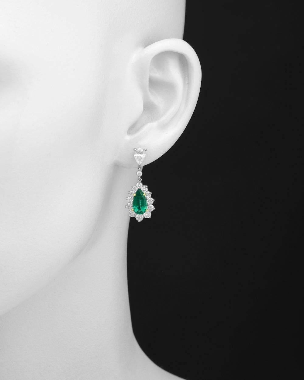 Emerald and diamond pendant earrings, showcasing a pair of pear-shaped emeralds weighing approximately 2.80 total carats, accented by a circular-cut diamond surround and suspended from a bezel-set circular-cut diamond to a pear-shaped diamond