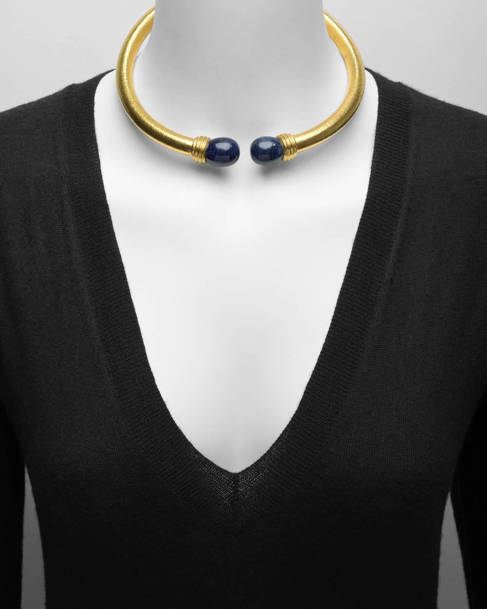 Torque collar necklace in hammered 18k yellow gold, with pair of large egg-shaped lapis lazuli terminals, made in Greece, signed Ilias Lalaounis. Hinged at back. Accompanied by the original necklace box.
