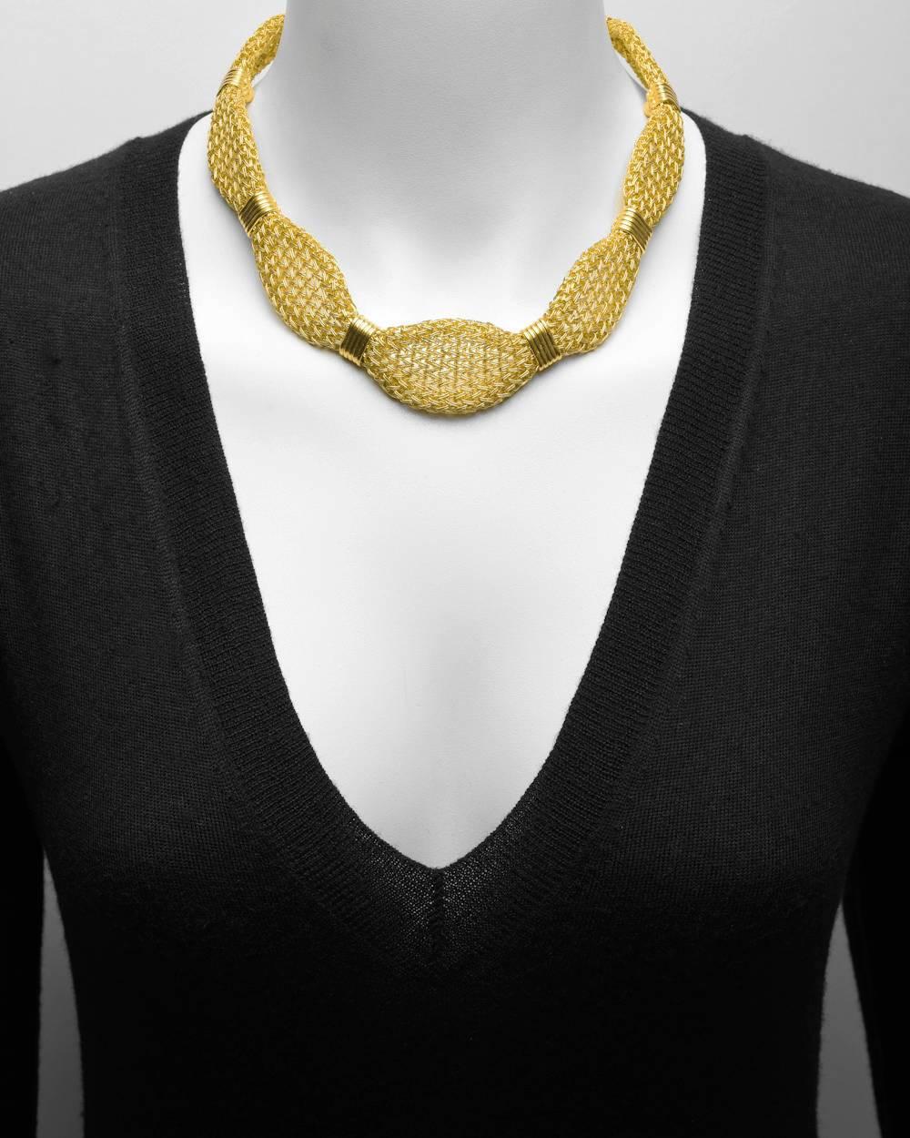 Woven gold necklace, pinched in at intervals with ribbed polished gold connectors and secured by a box clasp, in 24k yellow gold. 18.5" long and 238 grams.
