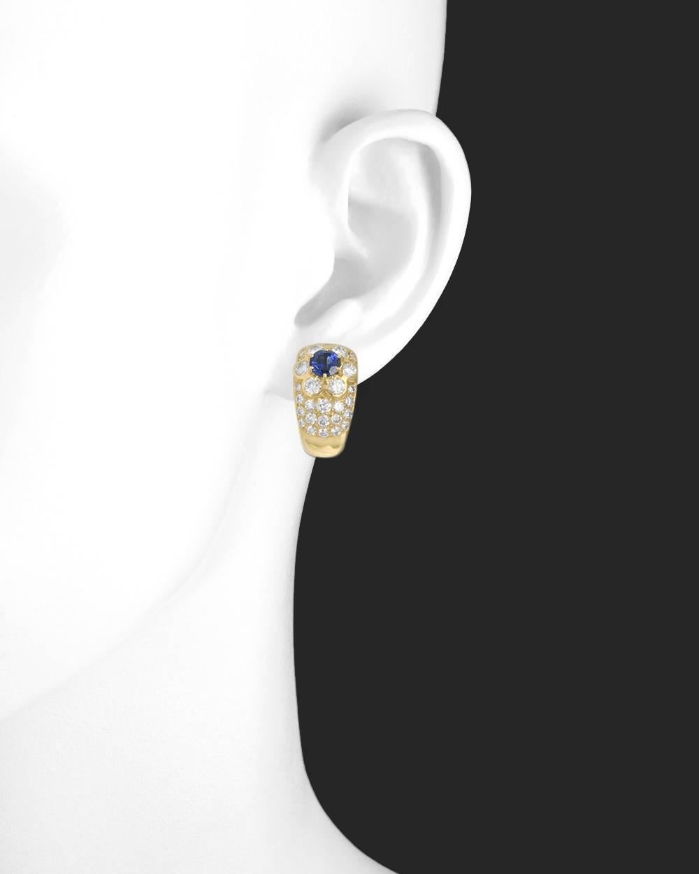 Vintage half-hoop earclips, designed with a round-cut sapphire and diamond-set flower motif at top, accented by pavé-set round brilliant-cut diamonds below,  in 18k yellow gold, numbered B3366F7 and signed 'VCA' for Van Cleef & Arpels. Sapphires