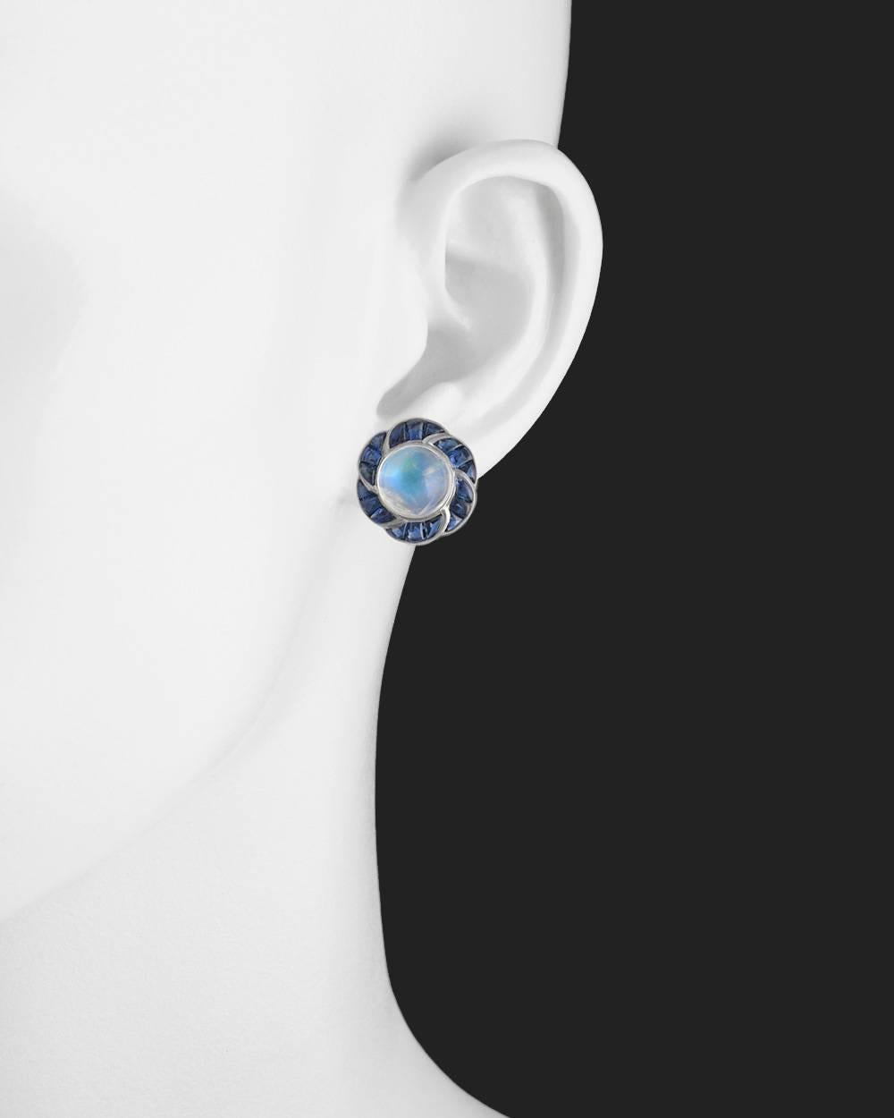 Flower motif earrings, centering a fine round cabochon-cut moonstone surrounded by calibre-cut sapphires, mounted in 18k white gold. Two moonstones weighing 9.95 total carats and 36 sapphires weighing 4.65 total carats. Posts with friction backs for