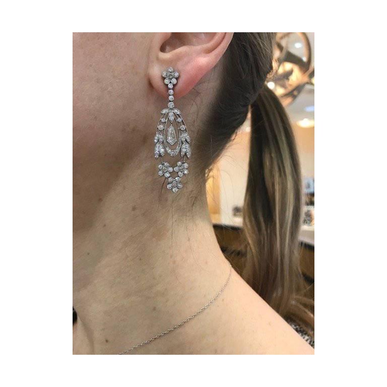 Drop earrings, showcasing diamond-set flower and trailing leaf motifs set with a round-cut diamonds and a larger shield-cut diamond at center, in 18k white gold. Diamonds weighing 2.57 total carats. Posts with friction backs for pierced ears. Just