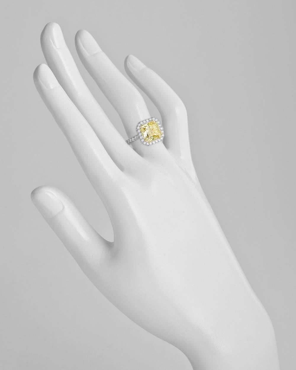 Yellow diamond engagement ring, centering a fine radiant-cut fancy yellow diamond weighing 4.01 carats with VS2-clarity, framed by round-cut white diamonds with partway round-cut white diamond-accented band, mounted in platinum and 18k yellow gold.
