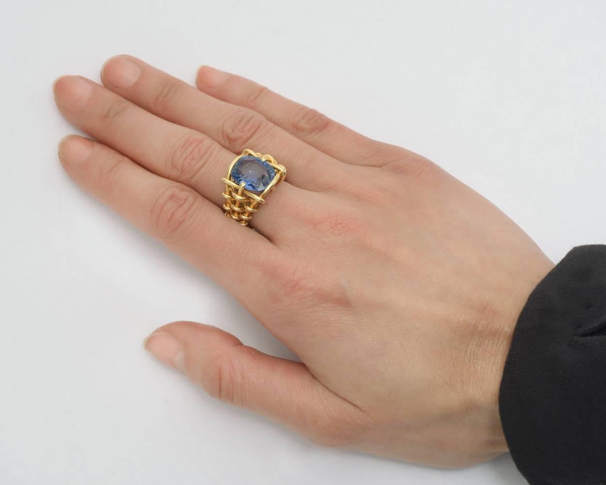 Sapphire cocktail ring, showcasing a cushion-shaped Ceylon sapphire weighing 6.18 carats, in a tapering basketweave patterned 18k yellow gold mounting, signed Verdura. Size 6.5.
