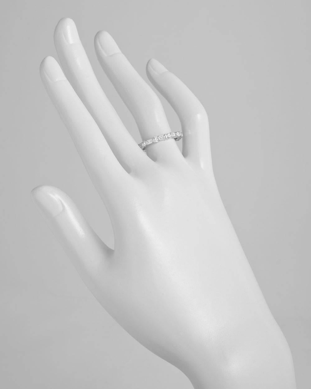 Round and emerald-cut diamond eternity band ring, the diamonds bar-set in platinum. Eleven round-cut diamonds weighing 0.70 total carats, alternating with eleven emerald-cut diamonds weighing approximately 0.76 total carats. 2.5mm band width. Size 6.