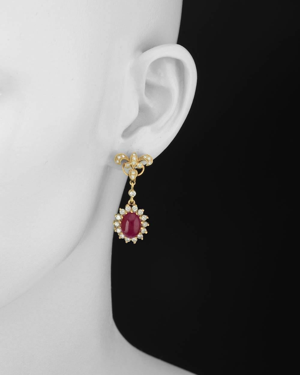 Ruby and diamond pendant earrings, showcasing a pair of larger oval-shaped cabochon-cut rubies weighing approximately 11.90 total carats, accented by round diamonds weighing approximately 1.20 total carats, mounted in 14k yellow gold, with posts and