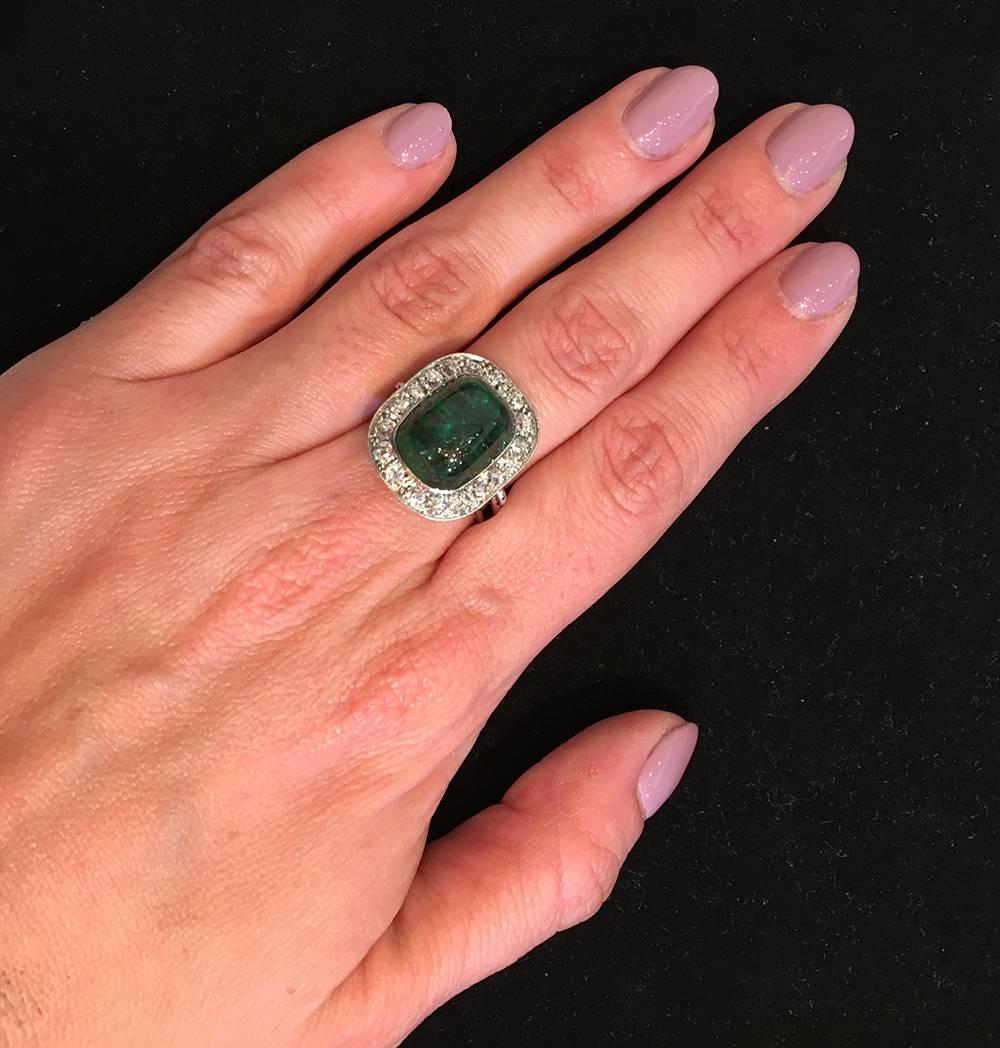 Emerald and diamond ring, centering a sugarloaf cabochon-cut natural emerald weighing approximately 9.76 carats, surrounded by eighteen round diamond accents weighing approximately 1.50 total carats, mounted in a platinum setting with a pierced