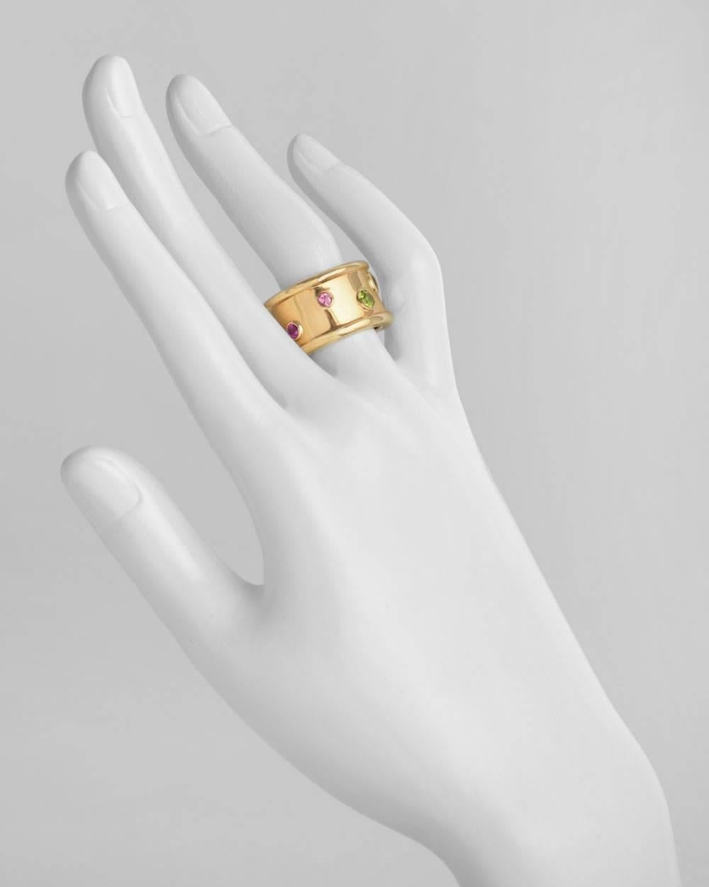 Wide band ring, accented by various sizes of bezel-set round peridot and pink tourmaline around the center, in polished 18k yellow gold, the band approximately 14mm wide, numbered 9C285, signed Chanel. Size 7.5.