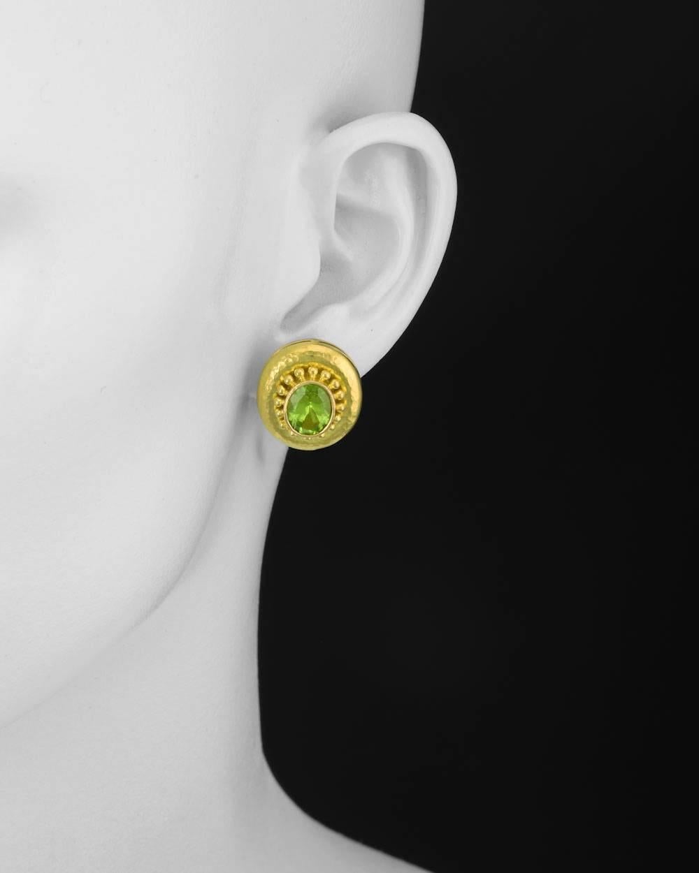 Oval-shaped peridot earrings, the peridot mounted in a hammered 18k yellow gold frame with beaded granulation, with clips and folding posts, signed Elizabeth Locke. 0.85