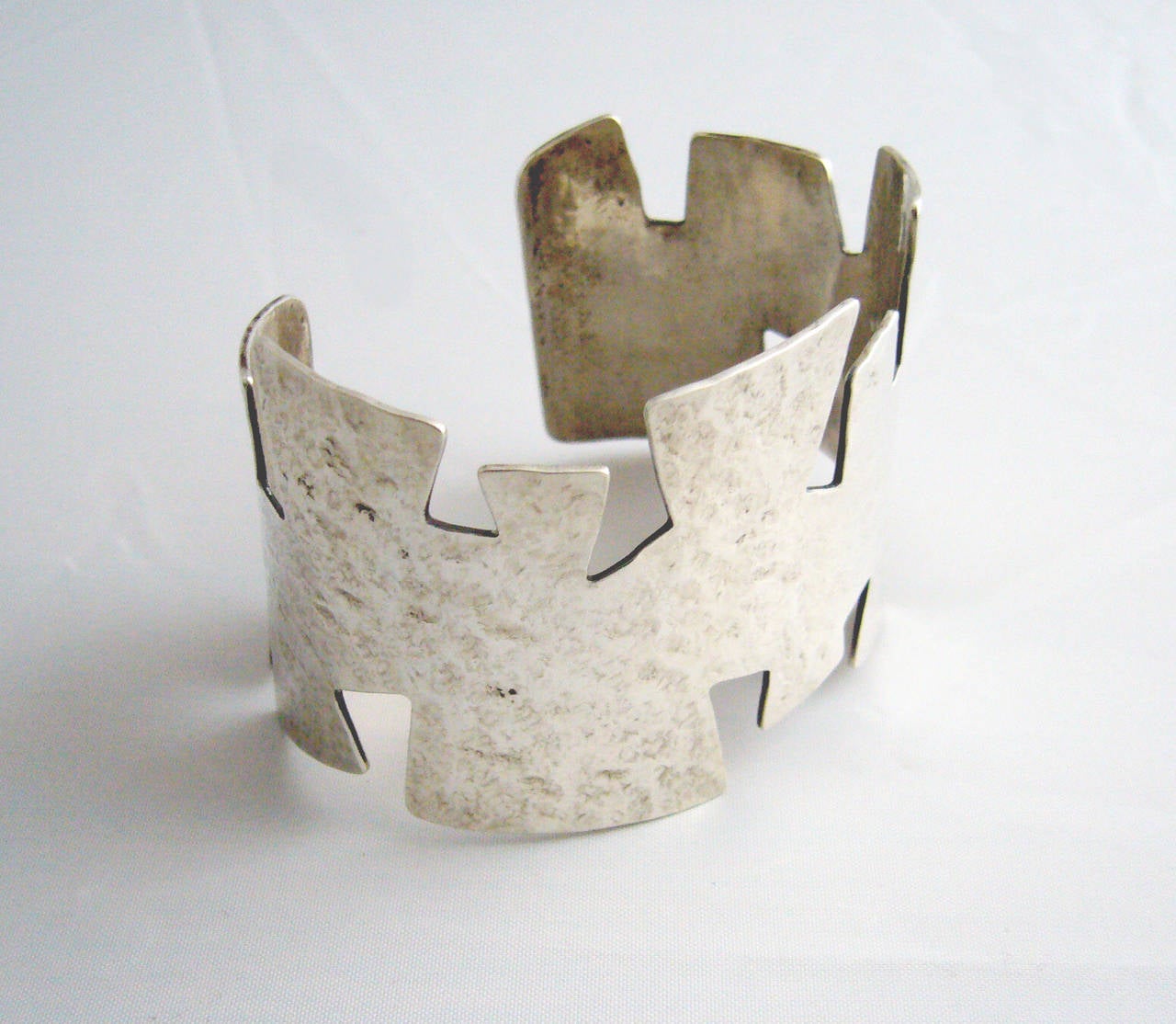 A sterling silver hand hammered cuff bracelet with puzzle cut out edges.  Bracelet has a wearable wrist size of 7