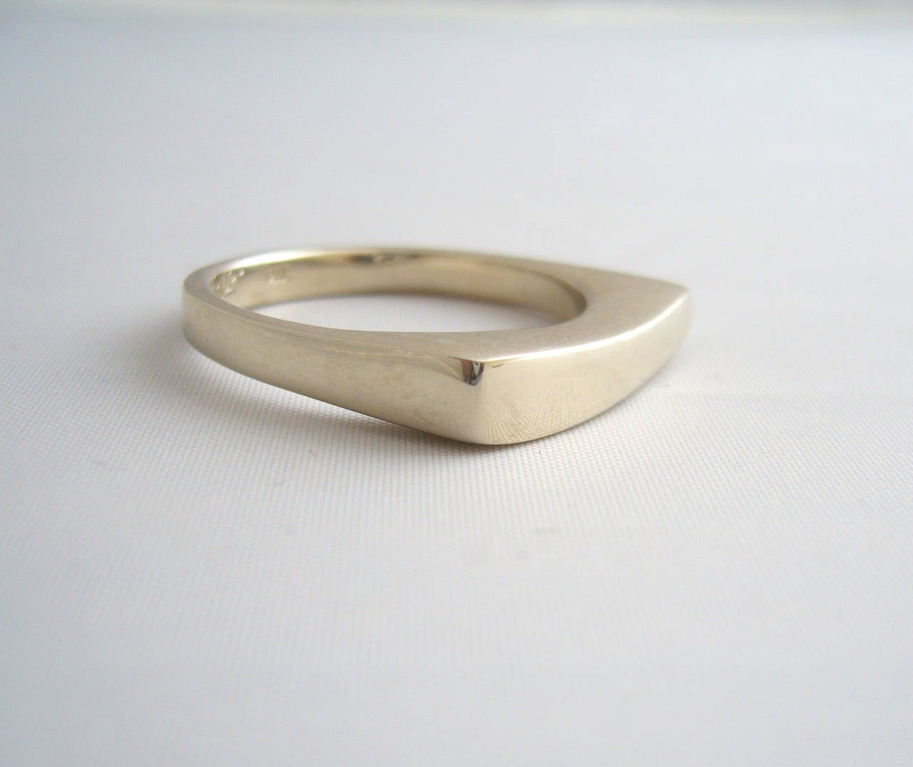 A 14k solid white gold minimalist ring created by Betty Cooke of Baltimore, Maryland.  Artistically sculpted with a graceful curve at top, this ring is suitable for a man or woman and for an engagement or wedding ring.  A finger size 10, signed
