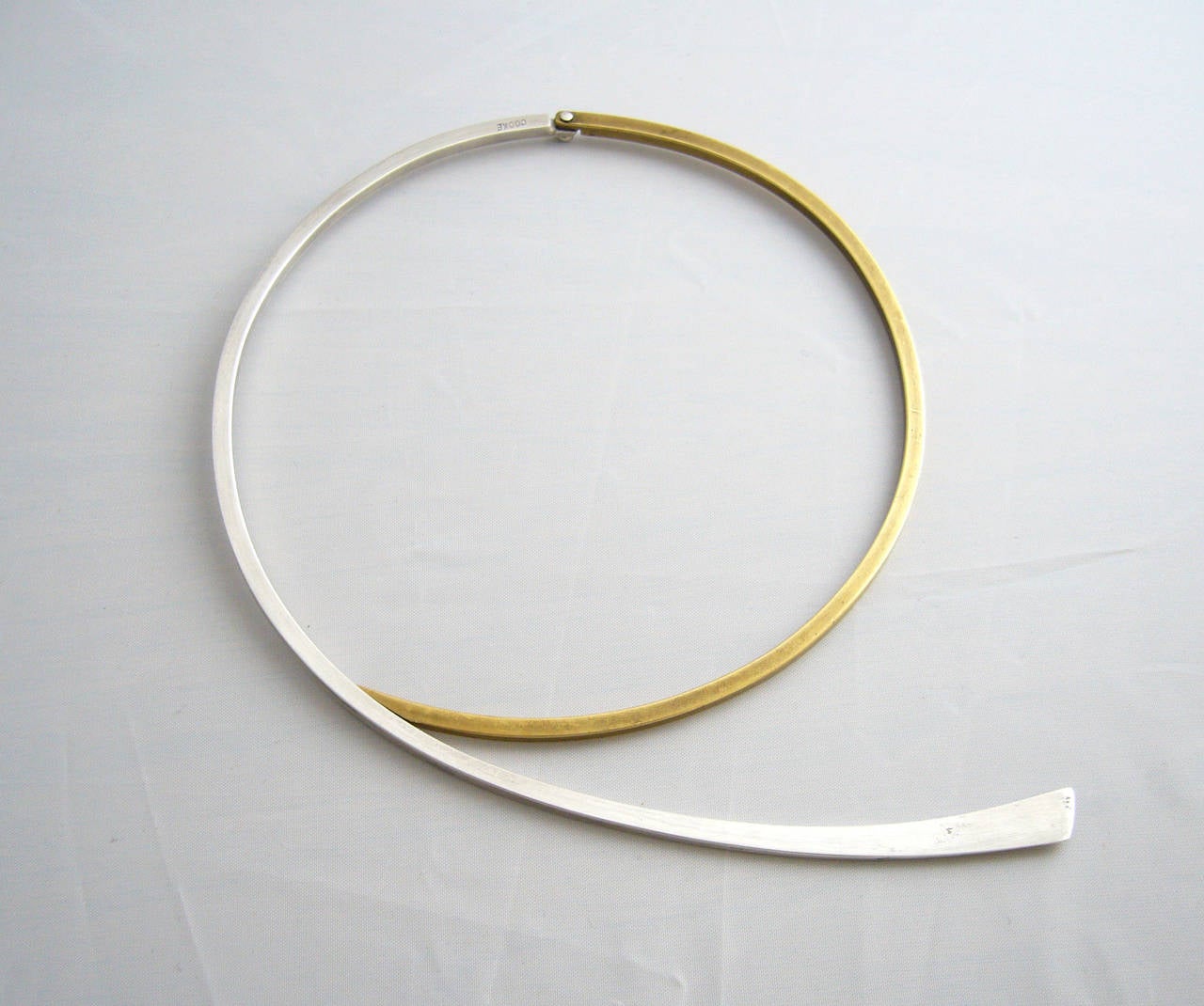 A hinged choker of sterling silver and brass made by Betty Cooke of Baltimore, Maryland.  Simplistic and classic in form, necklace has a wearable neck length of 15