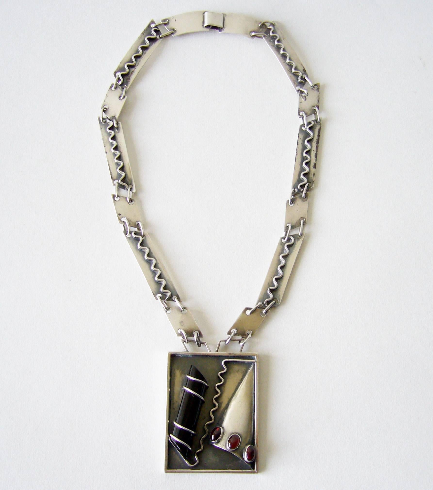 Rare, one of a kind sterling silver, onyx and amber or garnet surrealist necklace created by Idella La Vista of New York City, New York.  Necklace features a large piece of onyx threaded on to a sterling plaque along with other pieces of hand forged