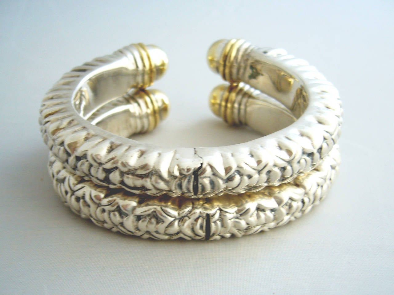 A pair of Bill Blass rope or cable style bracelets circa 1980's.  Bracelets are hinged at the back for comfort when putting them on. The are heavy, weighing a total of  195.5 grams and are made of sterling silver with 18k gold accents.  Made for a