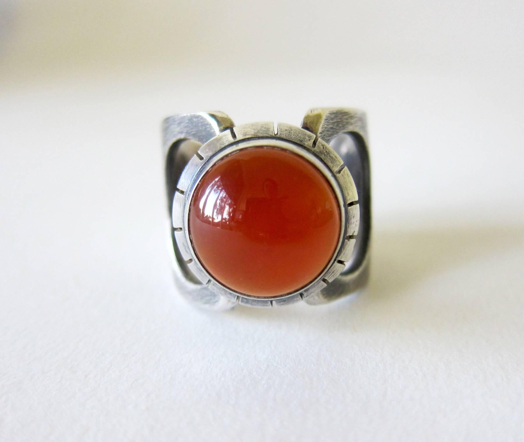 Handmade sterling silver modernist ring with carnelian cabochon created by James Parker of San Diego, California.  Ring is a finger size 11 to 11.5 and is signed with the artists' cypher of a conjoined JP.  Tests positive for silver and suitable for