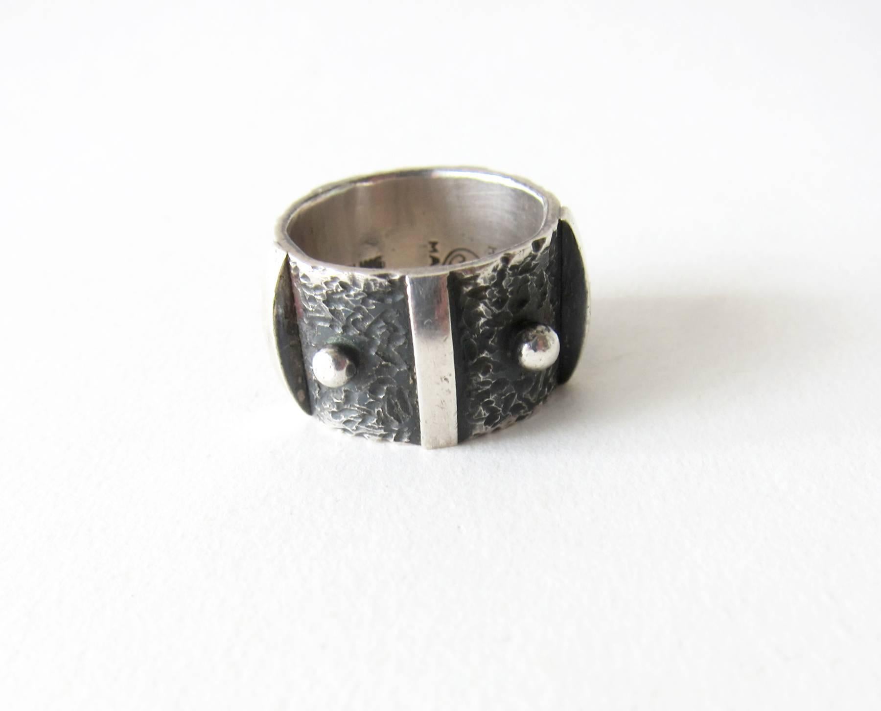 Sterling silver wide band ring featuring a studded design created by James Parker of San Diego.  Parker was an early member of the San Diego Allied Craftsmen Association which started in the 1940's.  His jewelry was featured in the show 
