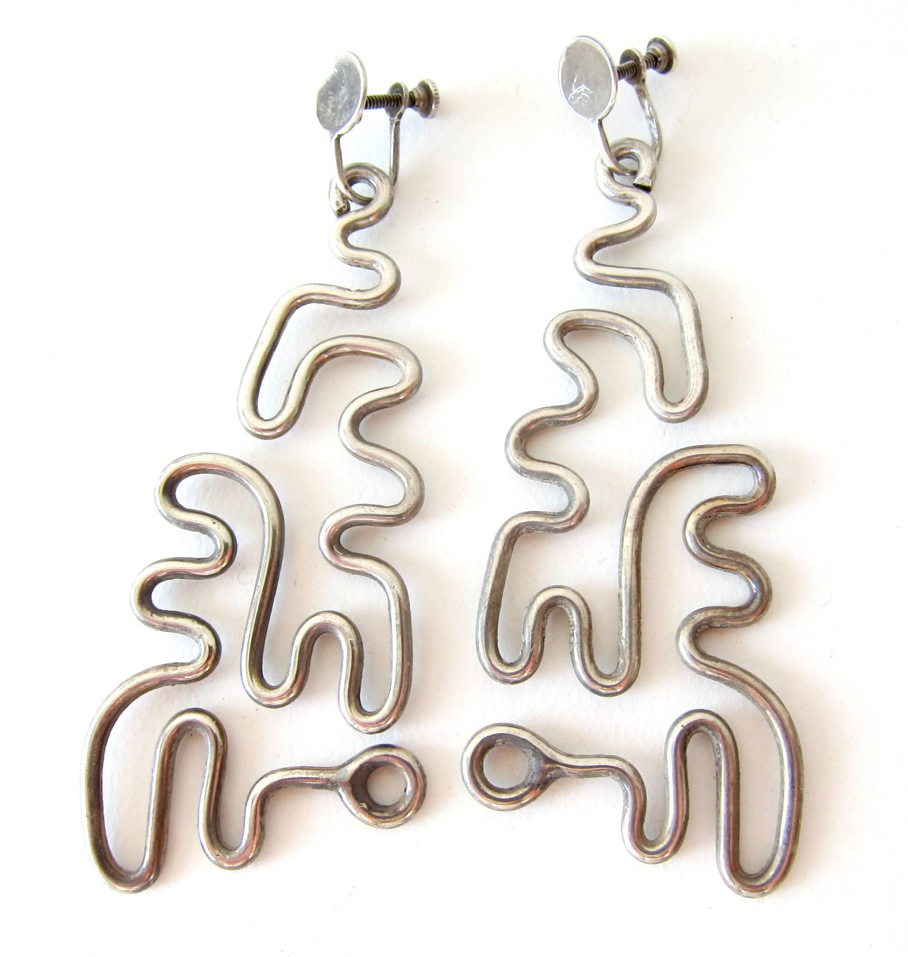 Sterling silver puzzle earrings created by Milton Cavagnaro of Mill Valley, California.  One continual piece of heavy gauge sterling silver makes up these highly creative earrings.  Earrings are of the screw back variety and measure 3.25" by