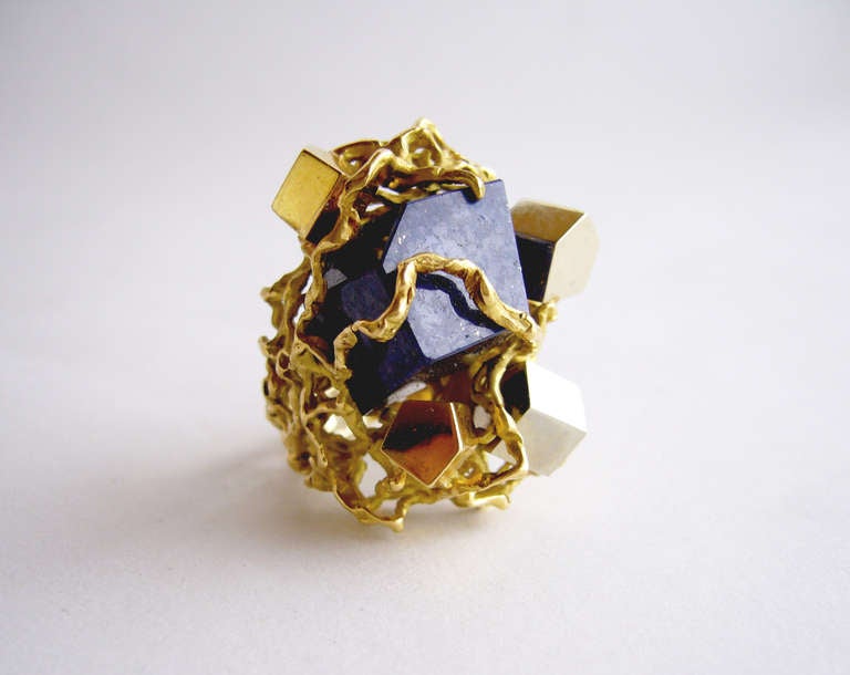 An 18k gold and lapis lazuli custom made ring, circa 1970's.  Ring is comprised of a pentagonal cut lapis surrounded by four tumbling cubes of 18k white and yellow gold all set within gold webbing.  Ring is a finger size 7.5 and stands 3/4
