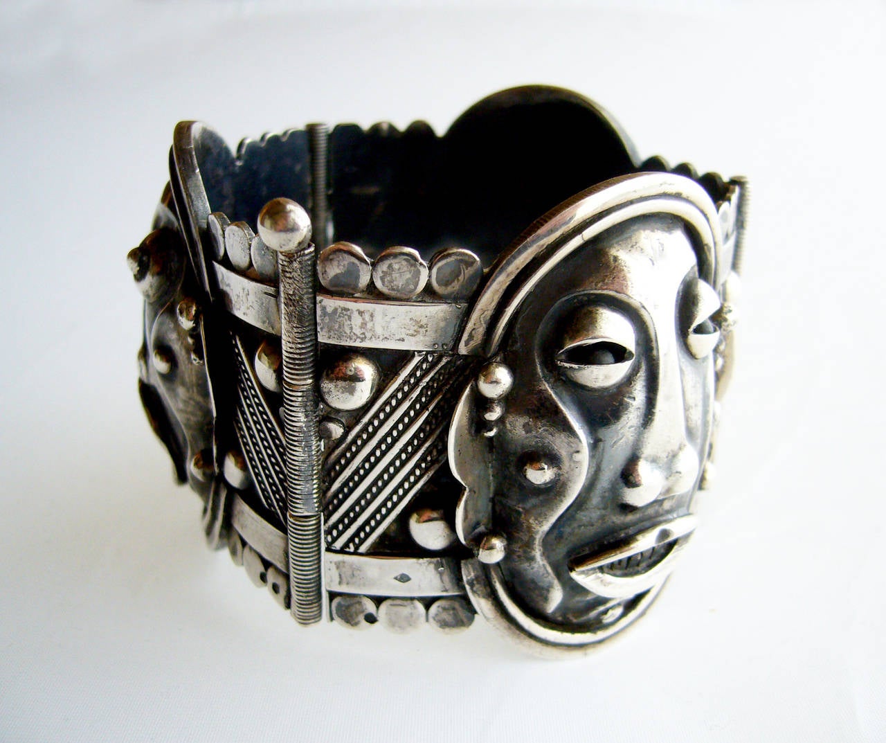 A large, silver linked cuff bracelet comprised of three masked panels including one with movable eyes.  Piece measures 2.25