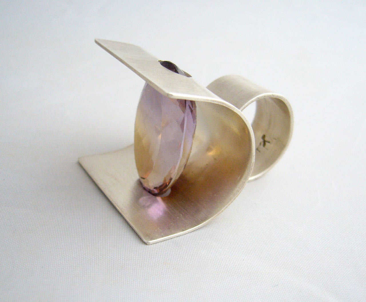 A faceted ametrine tension set within a curved piece of sterling silver, created by jeweler Heidi Abrahamson of Phoenix, Arizona.  Ametrine is a cross between an amethyst and citrine, this one being a beautiful example.  Ring has a very large
