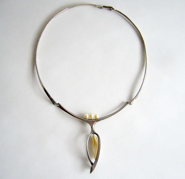A sterling silver and pearl modernist necklace created by Esther Lewittes of Los Angeles, California.  Hinged choker features three natural pearls and also incorporates a hanging tusk like form of mother of pearl within a sterling frame.  Necklace