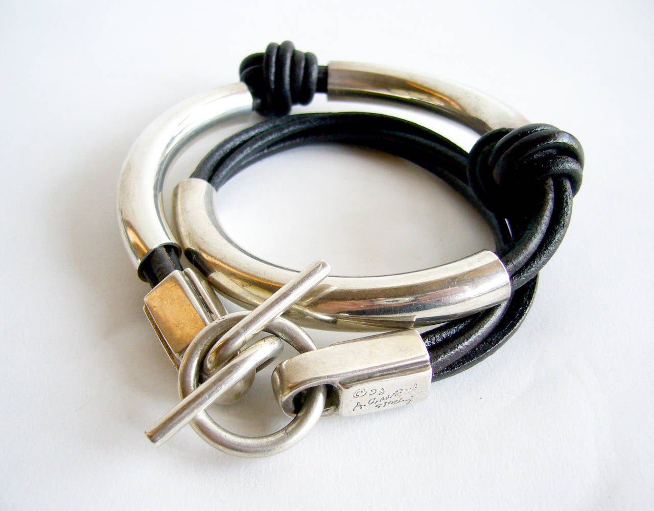 A sterling silver and knotted leather wrap around bracelet designed by Arnold Goldstein.  Bracelet measures 16