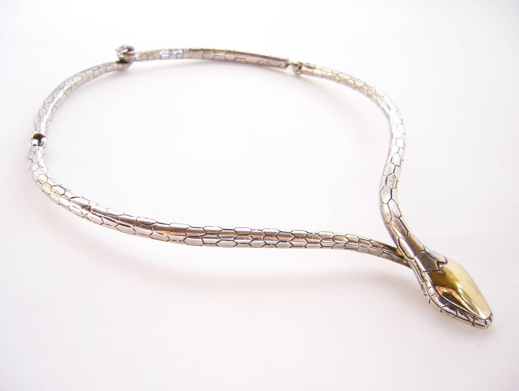 Sterling silver linked snake necklace created by José Maria Puig Doria of Barcelona, Spain.  Snakes head has a gold vermeil wash on it while the body of the piece has deeply textured skin and turned up tails to create the clasp. Necklace has a