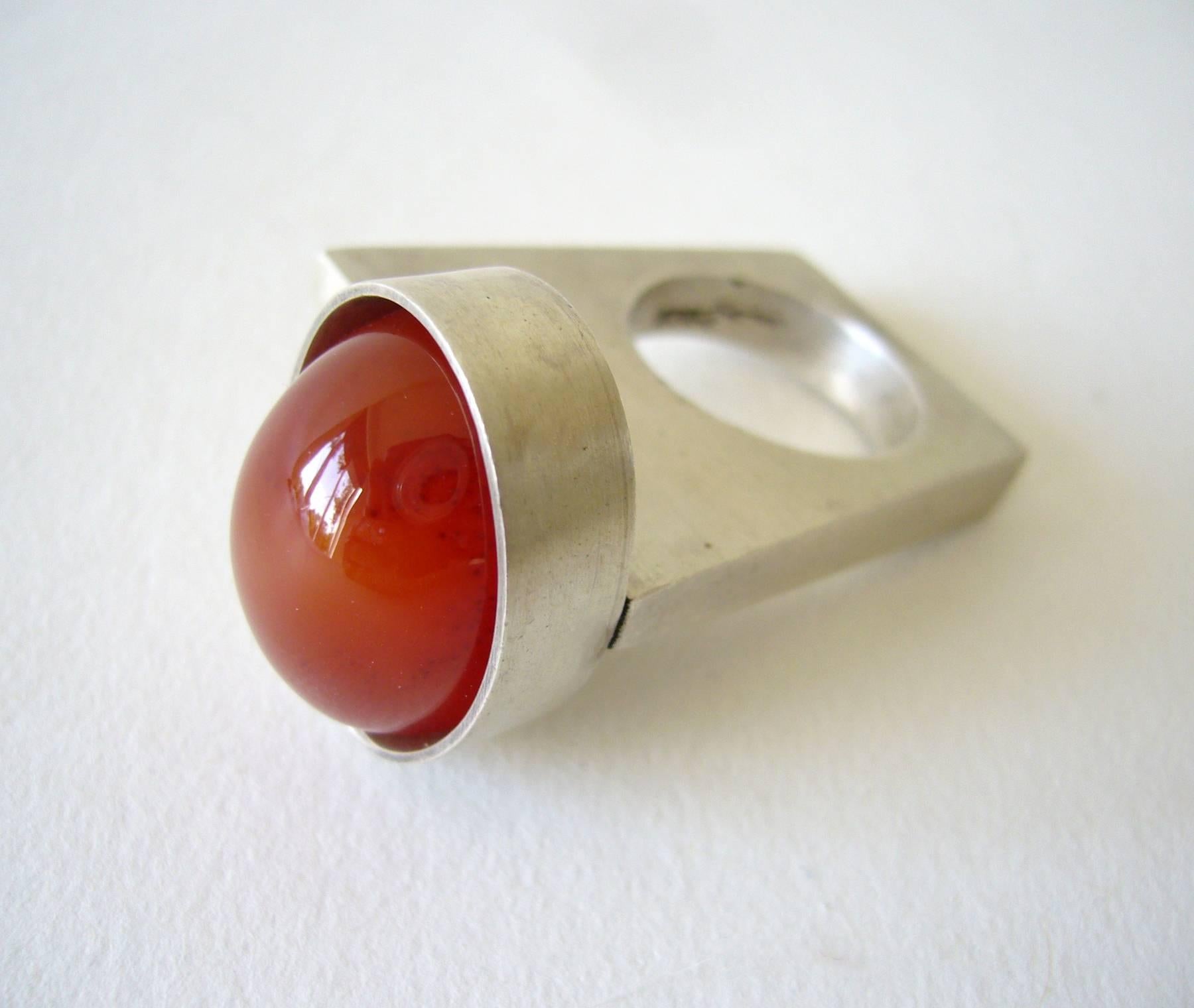 Large carnelian cabochon set within a sterling silver bezel on a shank of architectural form.  A finger size 6 and signed HHA, Heidi, 925.  In excellent condition.  
