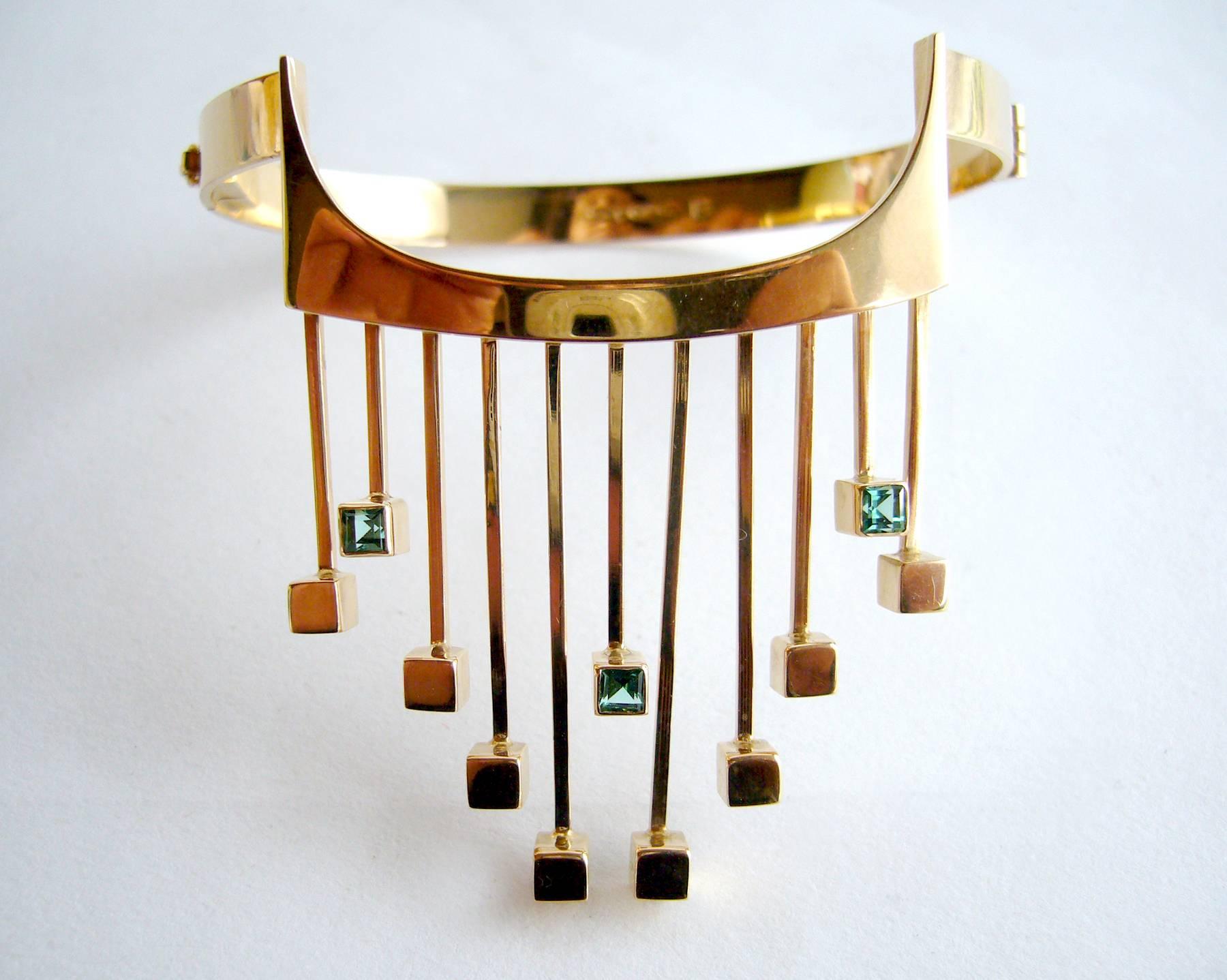 A rare, Finnish modernist 14k gold and tourmaline bracelet designed by Paula Häiväoja and executed by master goldsmith, Timo Nupponen.  Bracelet features golden fringe accented with square-cut greenish-blue tourmalines at the ends and a wearable