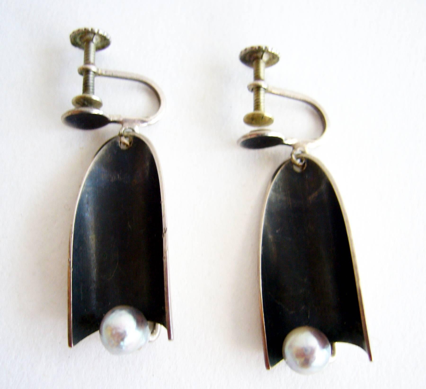 Kinetic sterling silver and grey pearl earrings created by modernist jeweler Jack Nutting of San Francisco, California.  Oxidized crescent shape swings within the setting for the pearl making a delicate sound in the ear when worn.  Screwback