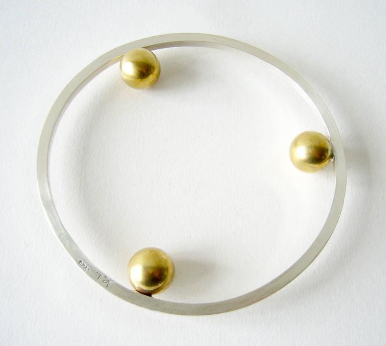 Sterling silver with brass ball bangle bracelet created by Heidi Abrahamson of Phoenix, Arizona.  Post modernist in style, the bracelet has a 3.25