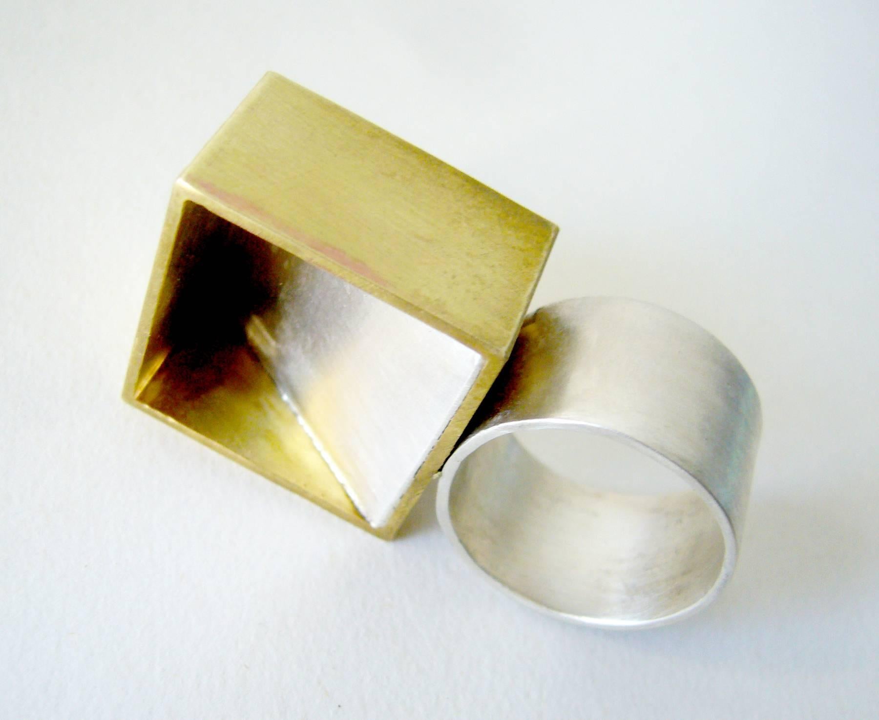 Geometric modernist sterling silver and brass ring created by Heidi Abrahamson of Phoenix, Arizona.  Ring features a brass square and a piece of slanted sterling silver within creating a shadowbox effect.  It sits about 1