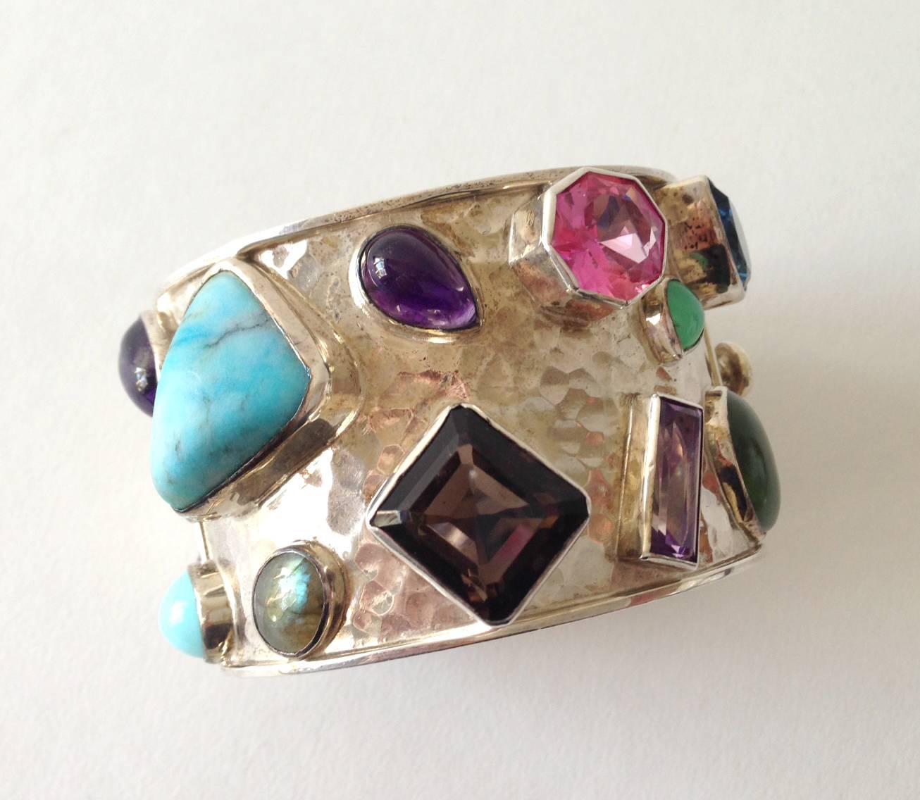 Multi colored semi-precious gemstones set in a sterling silver hinged cuff, created by Celia Harms of Mexico.  Each stone is bezel set within a hand hammered silver bracelet.  Bracelet has a wearable wrist length of 7"  and is 2" in width.