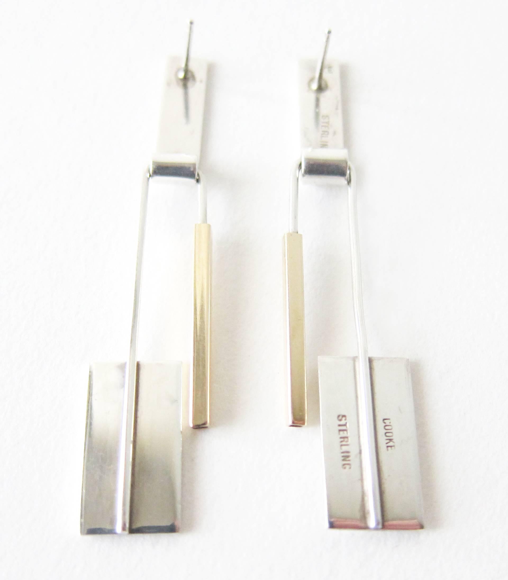 Timeless 14k gold and sterling silver earrings created by modernist jeweler Betty Cooke of Baltimore, Maryland.  Earrings have a swinging movement bottom section of sterling and gold, while the very top portion are partially brushed sterling silver.