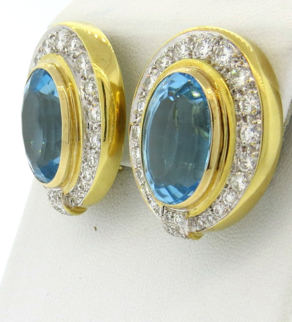 18k gold impressive earrings, featuring 18mm x 12.5mm blue topaz, surrounded with approximately 4.40ctw in VS1/H diamonds. Earrings are 30mm x 25mm. Weight - 30.1 grams