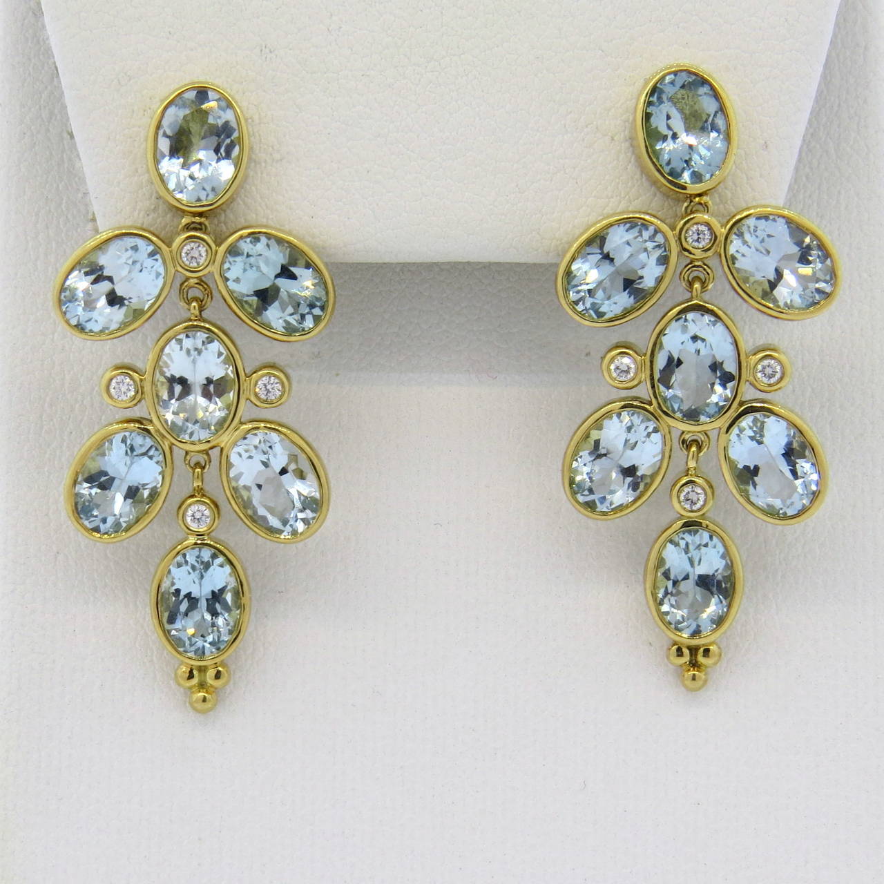 18k gold drop earrings by Temple St. Clair, featuring oval aquamarine gemstones and approx. 0.12ctw in G/VS diamonds. Earrings measure 40mm x 18mm. Marked 750 and with Temple hallmark. Weight - 14.6 grams and retail for $5500