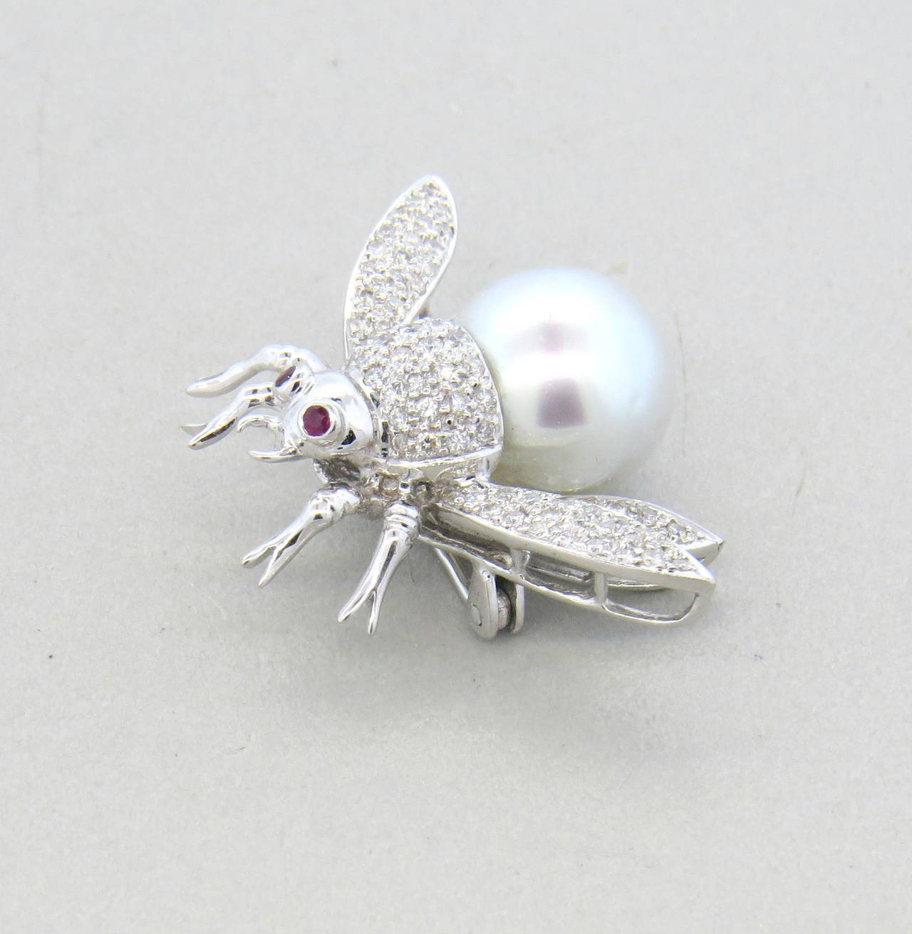 An 18k white gold bumble bee pin set with approximately 0.60ctw in G/VS diamonds, a 12.6mm south sea pearl and two ruby eyes.  The pin measures 25mm x 35mm and weighs 10.3 grams.
