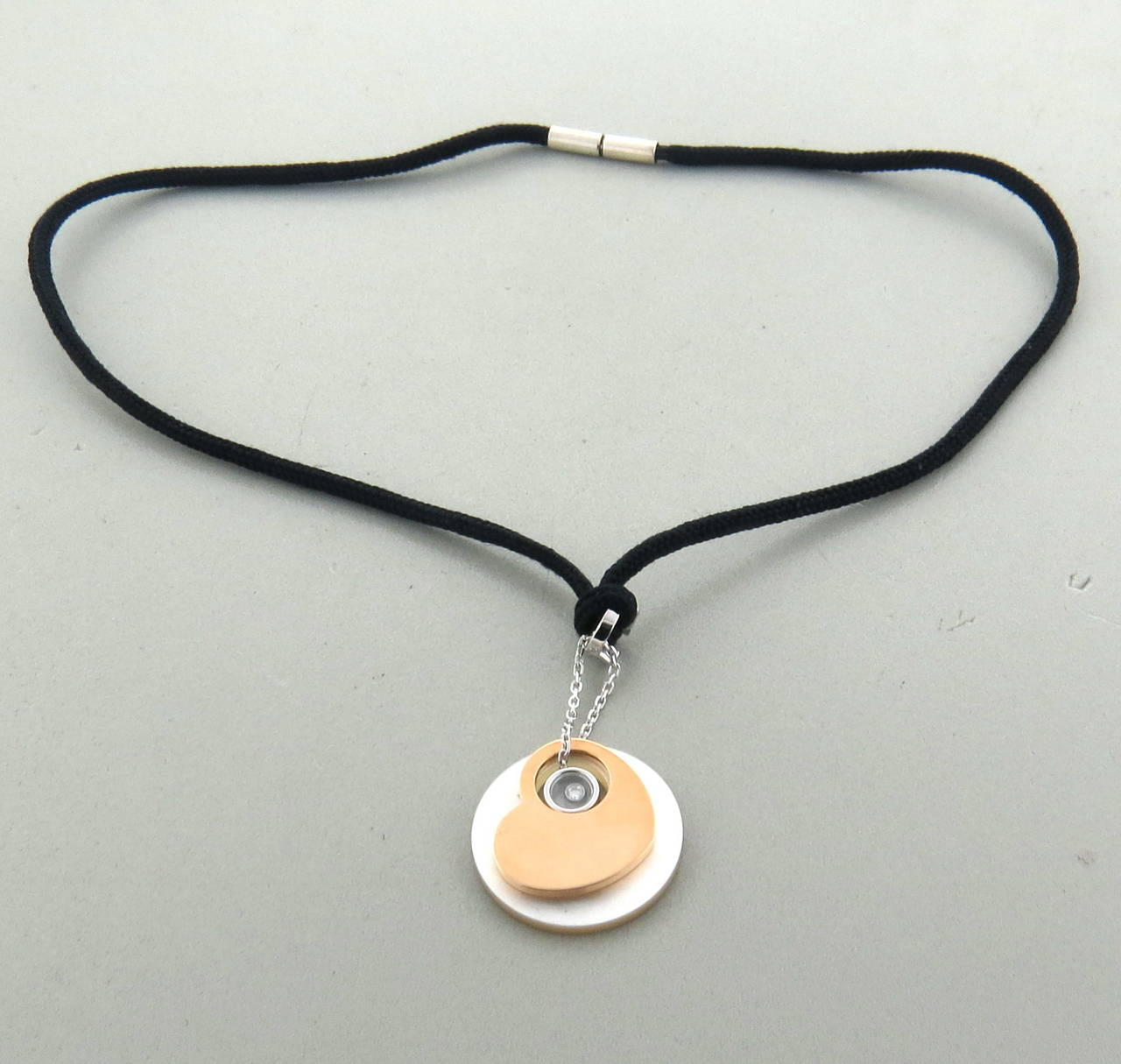 An 18k white and rose gold pendant / necklace which comes with a silk cord.  The pendant is made up of a mother of pearl disk, a rose gold heart and a floating diamond 0.05cts G/VS set in white gold.  Crafted by Chopard, the necklace measures  16