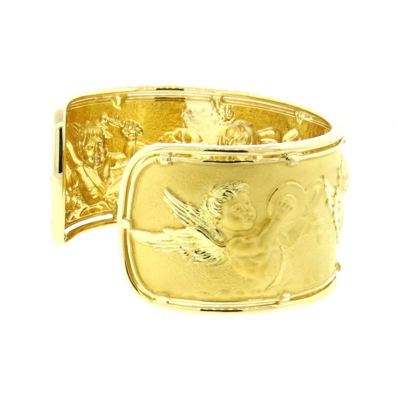 An 18k yellow gold cuff bracelet depicting cherubs playing musical instruments.  Crafted by Carrera y Carrera, the bracelet is 36mm wide and comfortably fits up to a 7