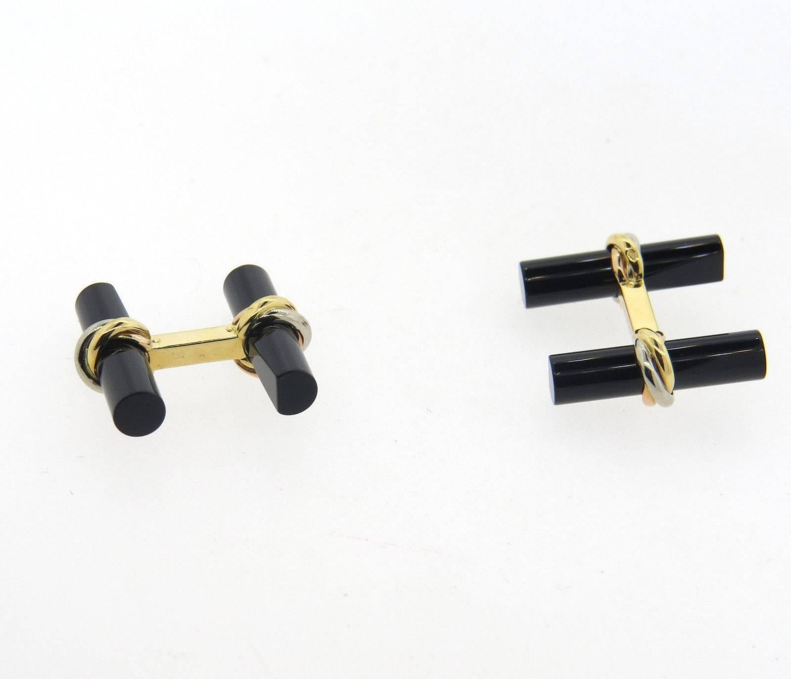 A pair of 18k yellow white and rose gold cufflinks set with onyx.  Crafted by Cartier, the cufflinks measure 22mm x 9mm and weigh 10.5 grams.  Marked:	Cartier, 750, K 14217.