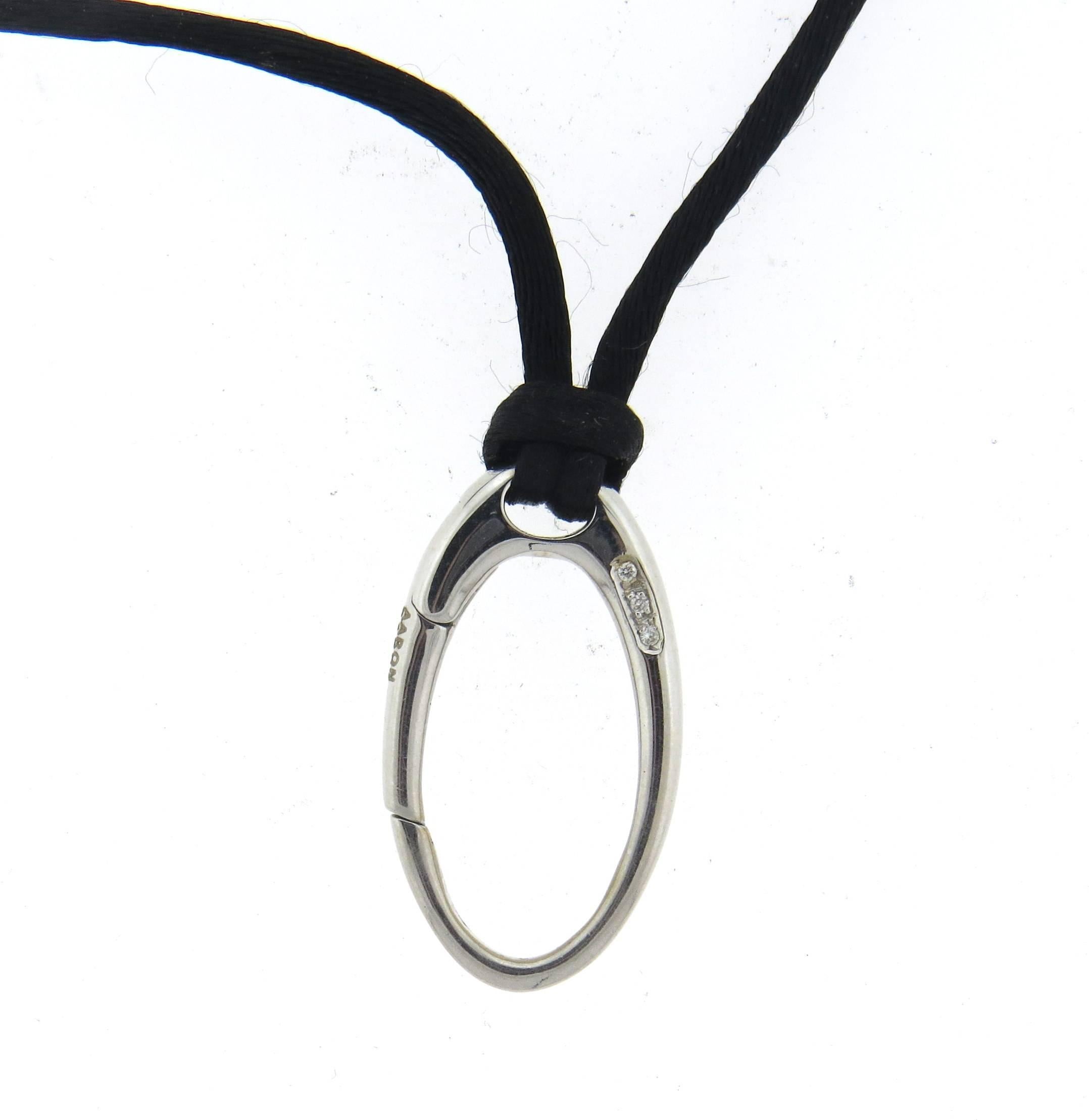 18k white gold charm pendant, suspended on a black silk cord, crafted by Aaron Basha, adorned with diamonds. Necklace is 16