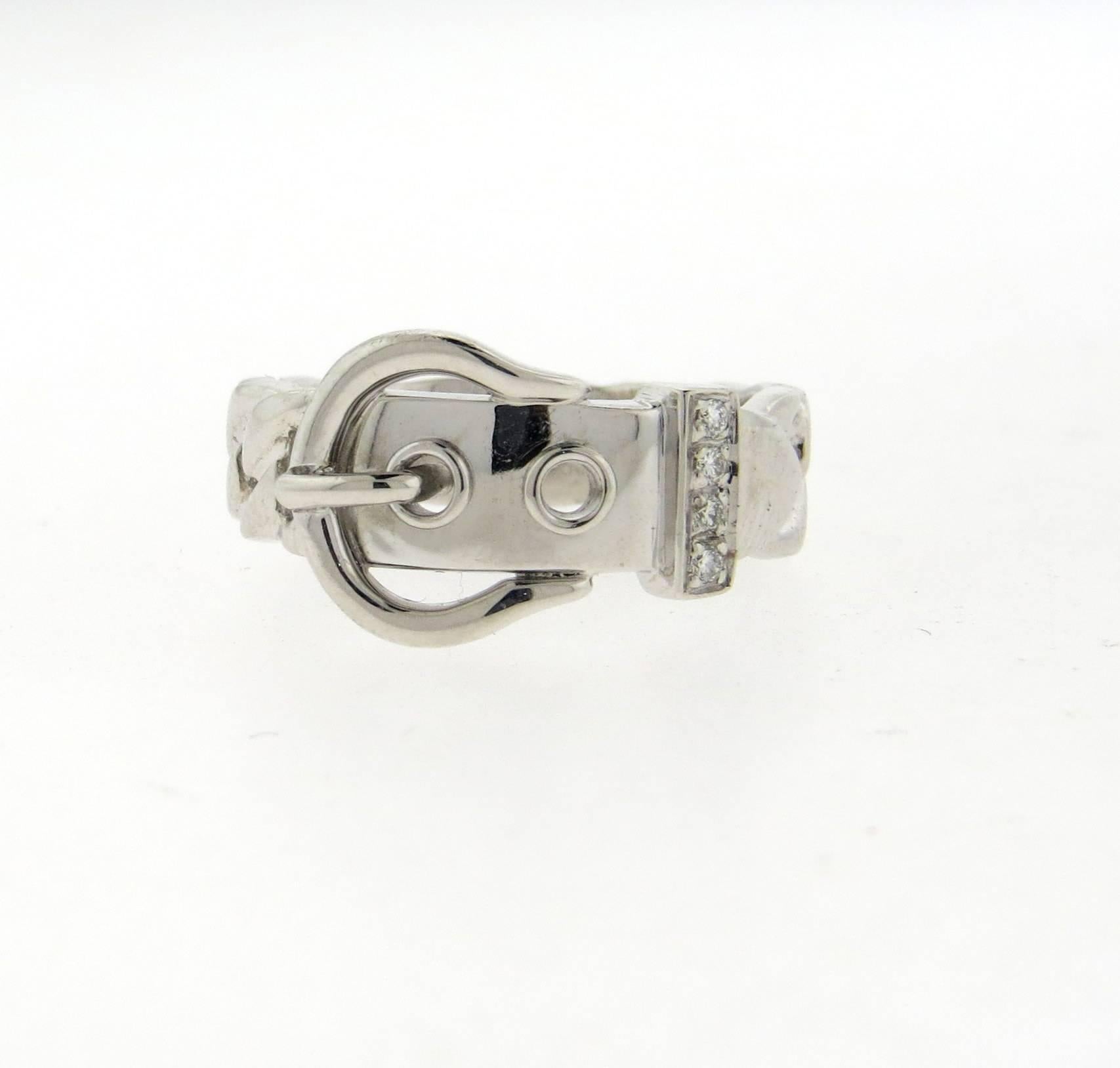 An 18k white gold band ring, crafted by Hermes, featuring buckle design, adorned with 0.04ctw in diamonds. Ring size 6, widest point is 10.5mm. Marked: Hermes, 0414476, 51, au750. Weight of the piece - 6.5 grams 