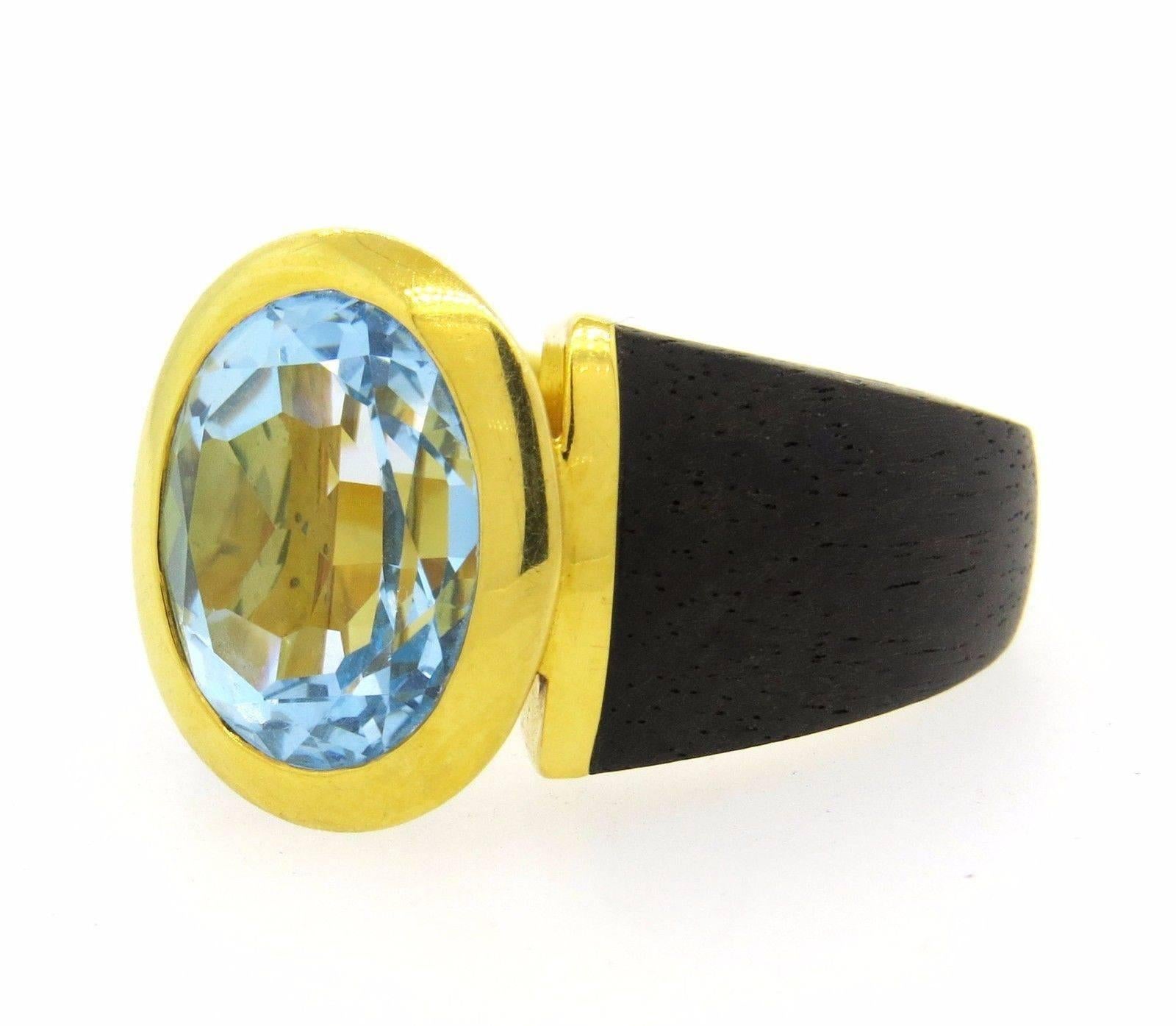 An 18K yellow gold and wood ring set with a blue topaz.  Crafted by Lotus Arts de Vivre, the ring is a size 6 and 17.8mm at the widest point.  The weight of the ring is 15.4 grams. Marked: Makers Mark, 18K.