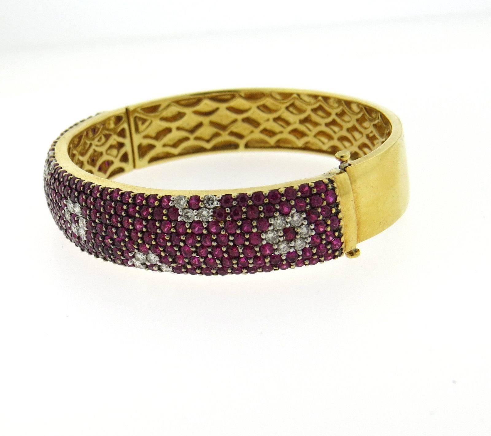 An 18k yellow gold bangle bracelet set with rubies and approximately 0.50ctw of H/VS diamonds.  The bracelet will comfortably fit up to  6 3/4