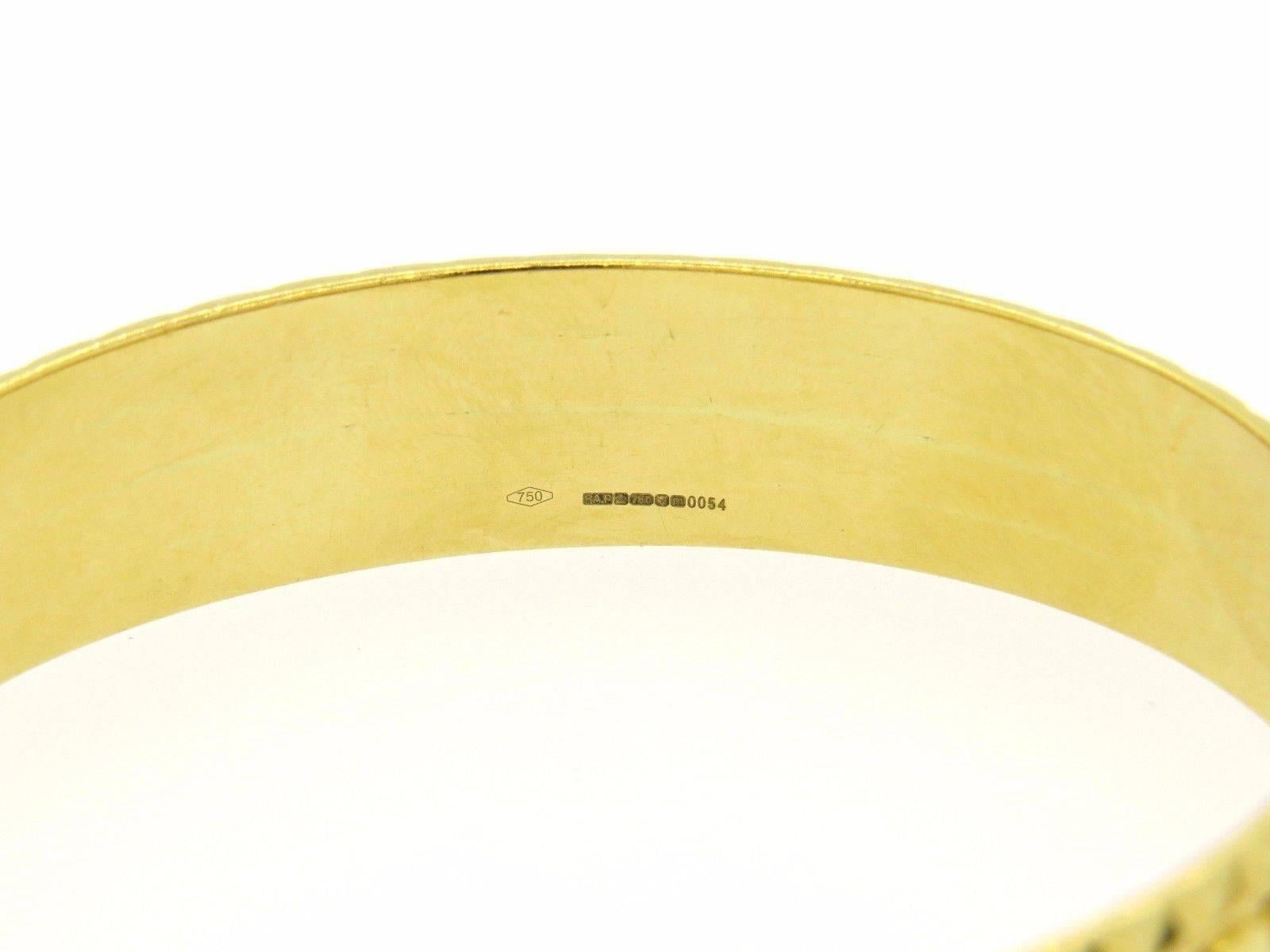 An 18K yellow gold bangle bracelet.  The bangle has interior dimensions of 68mm x 59mm and measures 15mm wide.  The weight of the piece is 62.9 grams. 